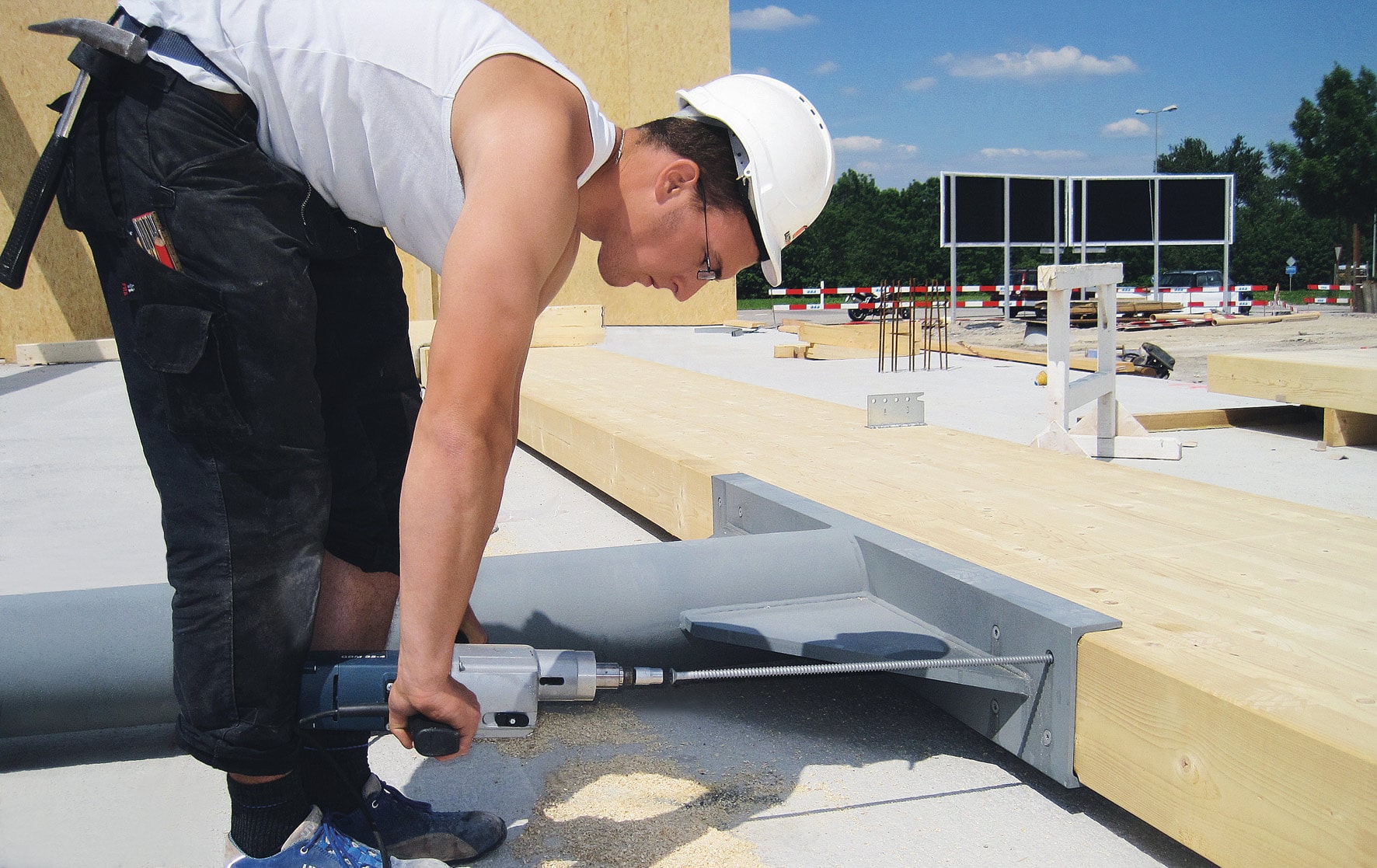 Ein Metallträger wird an einem Holzbalken verschraubt